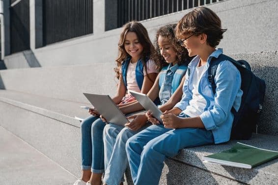 Happy school children, teenage boys using a tablet.