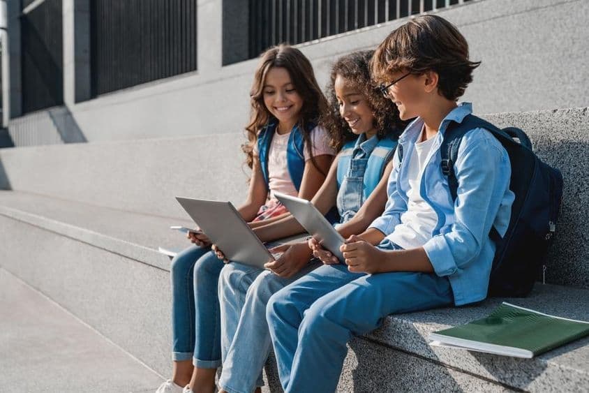 Happy school children, teenage boys using a tablet.
