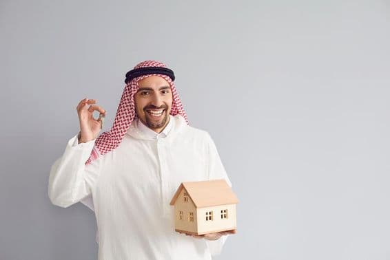 Arab male real estate agent holding a house model.