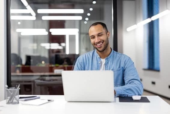 A happy young professional smiling while working on a computer.
