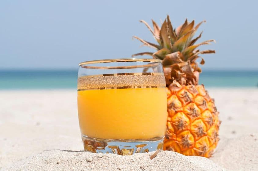 A glass of pineapple juice on the beach.