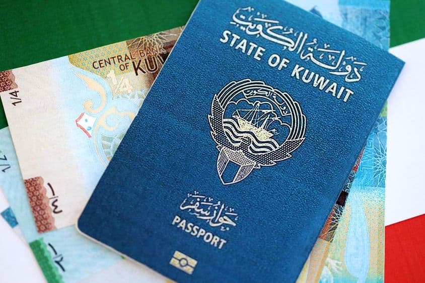 Kuwaiti dinar and passport lying on a table.