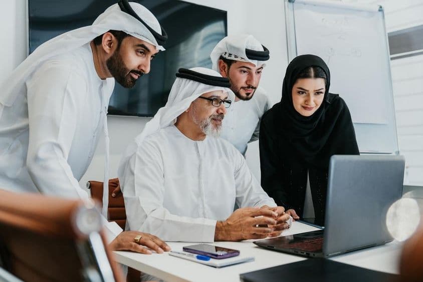 A group of Middle Eastern corporate businesspeople in traditional Emirati attire.