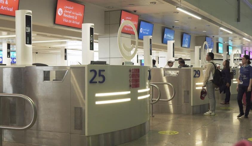 Passengers in the visa application submission zone at Dubai International Airport.