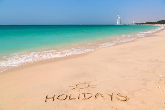 Holiday sign on a beach with turquoise water.