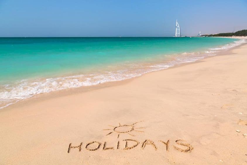 Holiday sign on a beach with turquoise water.