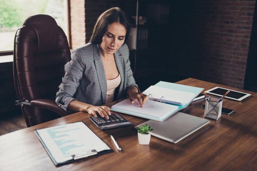 Successful woman checking documents at a desk before submitting to tax authority.