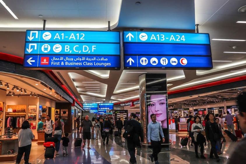 Passengers walking towards the departure gates at Dubai International Airport (DXB).