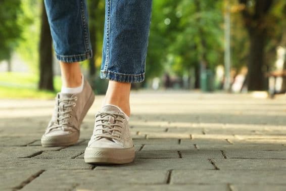 Woman walking in stylish sneakers on city street.