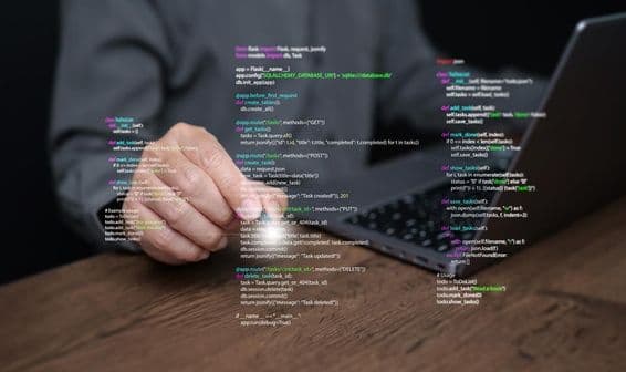 A programmer's hands on a laptop with coding.