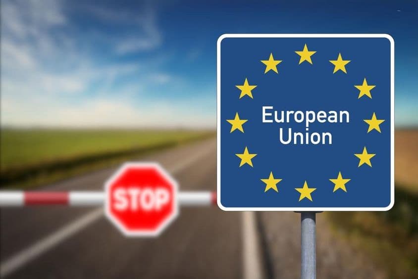 European Union emblem and a border crossing with barrier and stop sign.