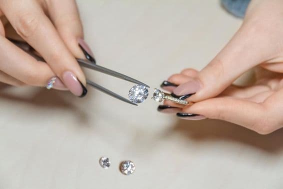 A jeweler's woman's hands holding a gemstone.