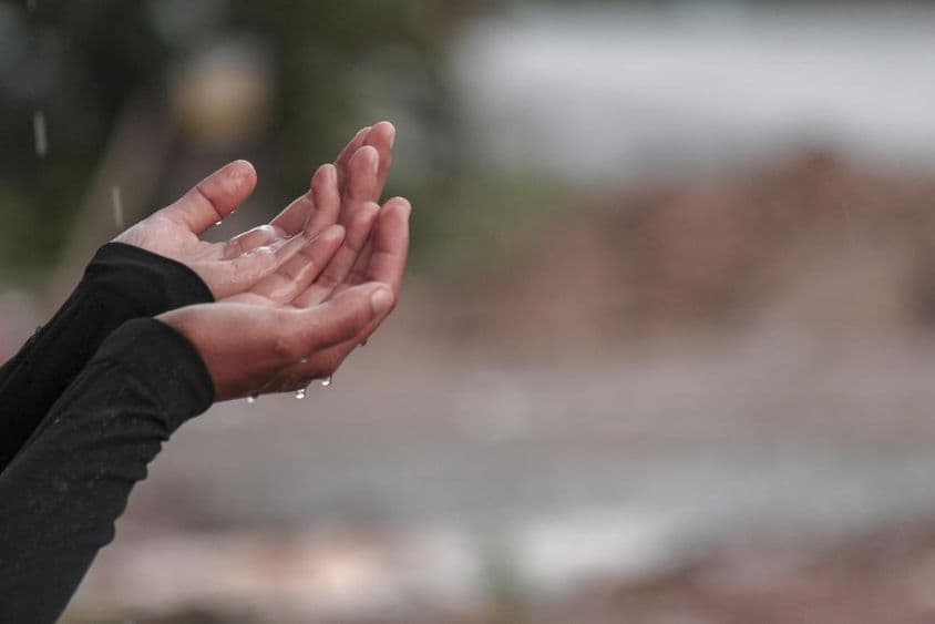 A woman praying with hands for rain.