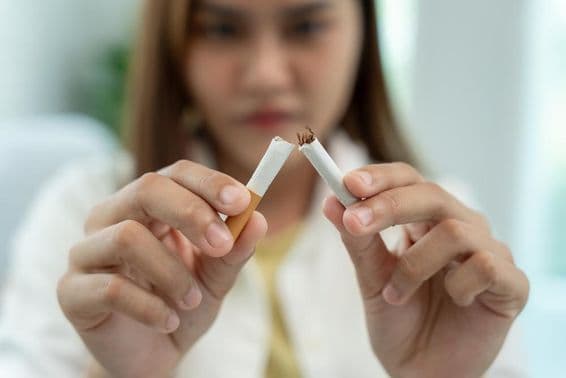 No smoking, a woman breaks a cigarette in half.