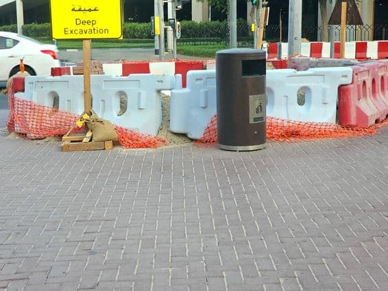 The road repair is surrounded by plastic barriers and an orange safety net.
