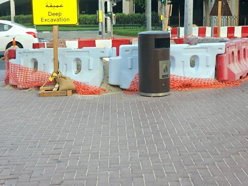 The road repair is surrounded by plastic barriers and an orange safety net.