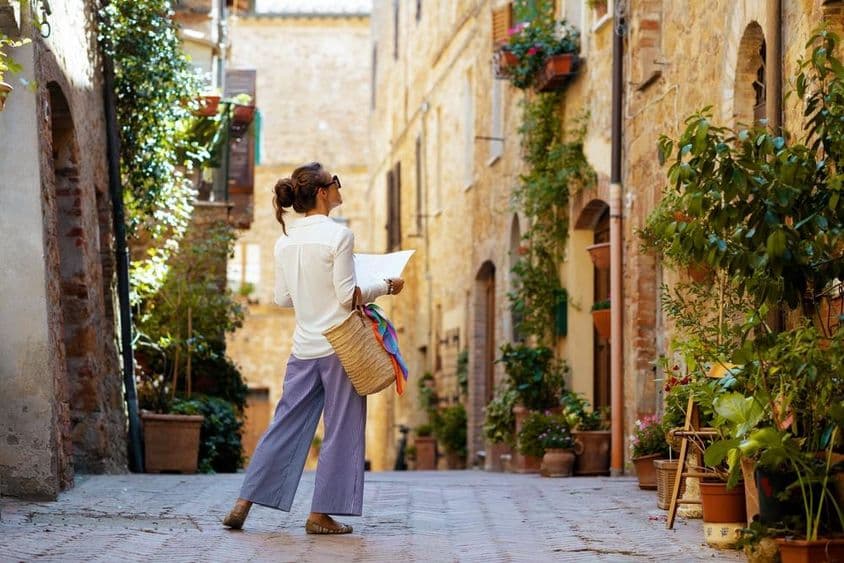 A woman with a map and a straw hat, enjoying the promenade in Tuscany, Italy.