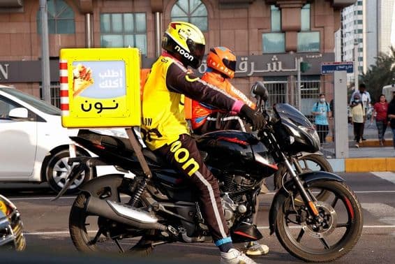 Motorcycle courier delivering in Dubai street.