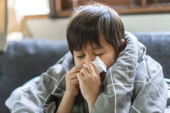 Young Asian boy sneezing and having a runny nose.