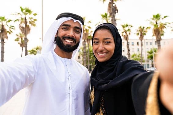 Traditional Arab couple in Emirati attire dating outdoors.