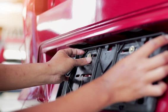 Mechanic changing the car's license plate at a service center.
