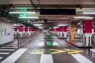 A spacious, empty, modern parking garage in Dubai with bright lighting and clear signage.