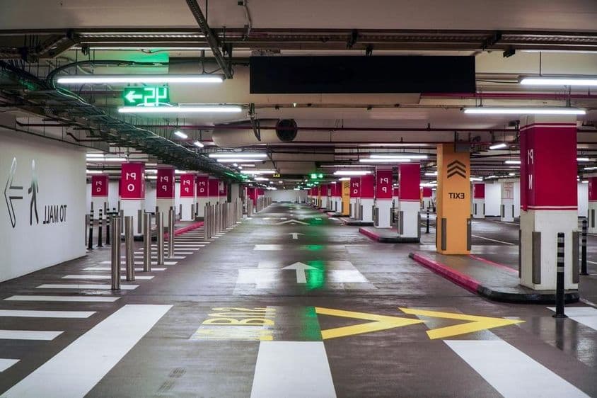 A spacious, empty, modern parking garage in Dubai with bright lighting and clear signage.