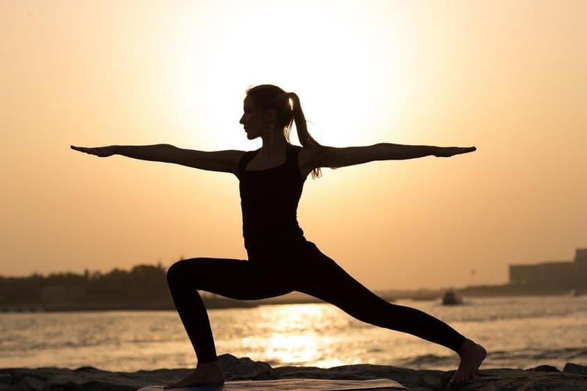 A woman practicing yoga at sunset in Dubai.