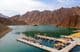 Beautiful deep green Hatta Lake surrounded by the Hajar mountains.