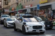 Waymo robotaxi navigating the busy, narrow streets of San Francisco's Chinatown.