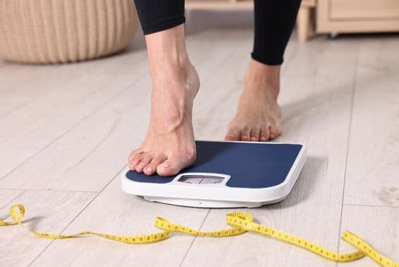 Woman stepping onto a bathroom scale.
