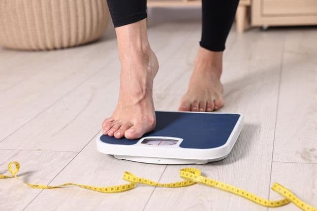 Woman stepping onto a bathroom scale.