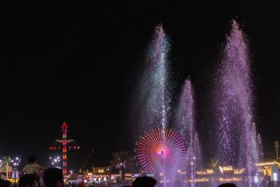 The vibrant night scene at the Sheikh Zayed Festival with water fountains.