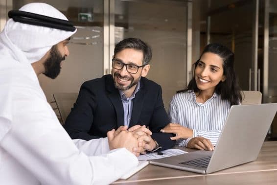 A happy Latin couple meeting with an Arab real estate agent.