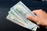 A bundle of dollars in a man's hand.