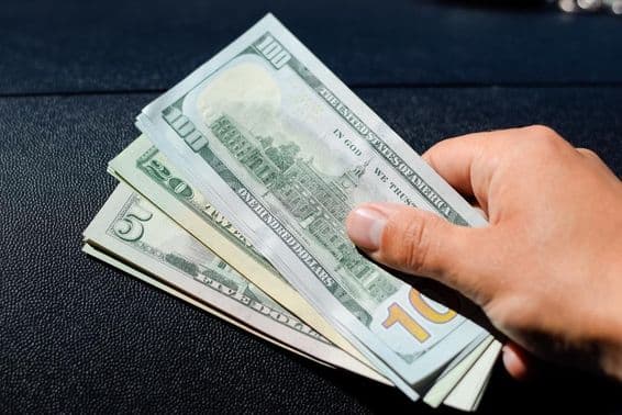 A bundle of dollars in a man's hand.