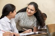 Indian teacher assisting a student during primary school classes.