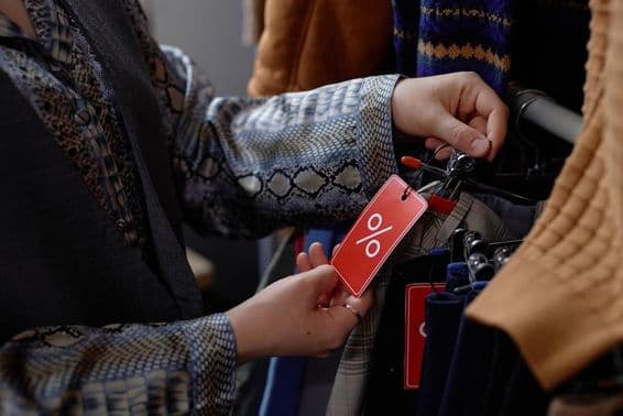 Woman in vintage attire selecting second-hand clothes.