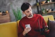 A young man relaxing at home with a smartphone and router, enjoying a peaceful afternoon.