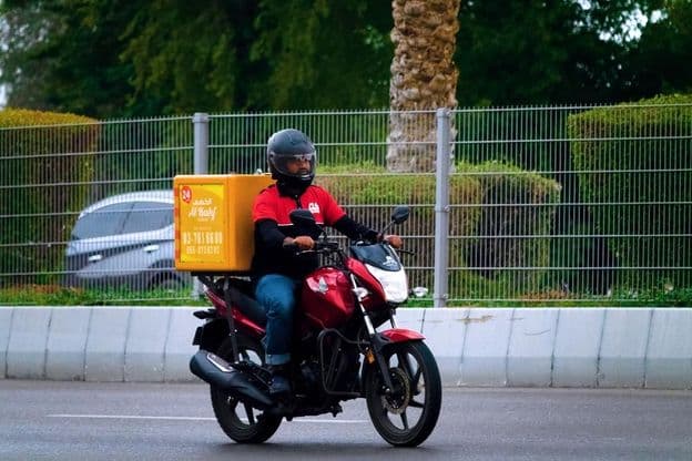Food delivery by motorcycle courier in Dubai.