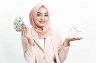 Muslim businesswoman holding money for house purchase.