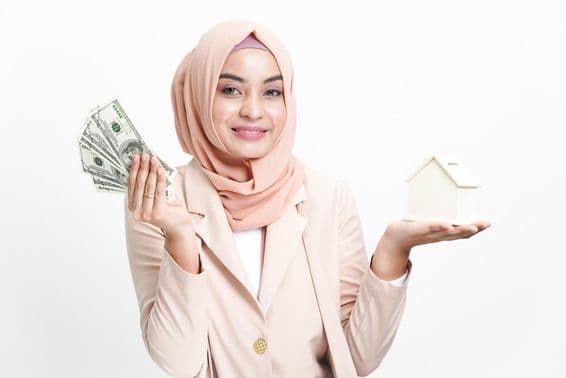 Muslim businesswoman holding money for house purchase.
