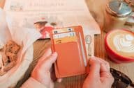 A brown leather cardholder containing identity cards, bank cards, and credit cards.