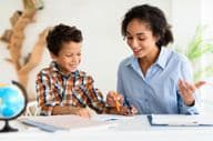 Young female teacher explaining a lesson to a young boy.