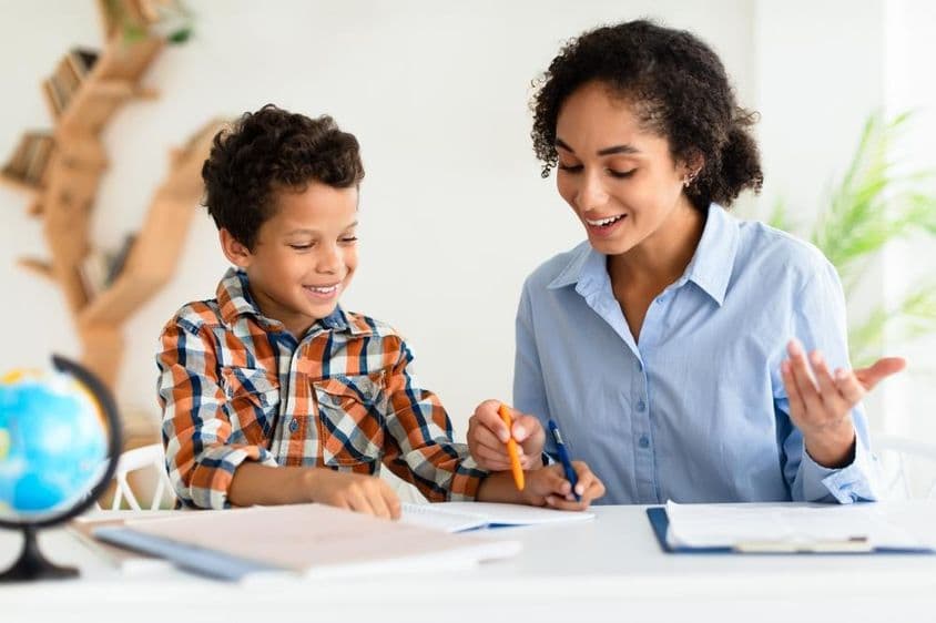 Young female teacher explaining a lesson to a young boy.