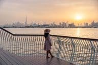 Young woman gazing at Dubai skyline under sunset.
