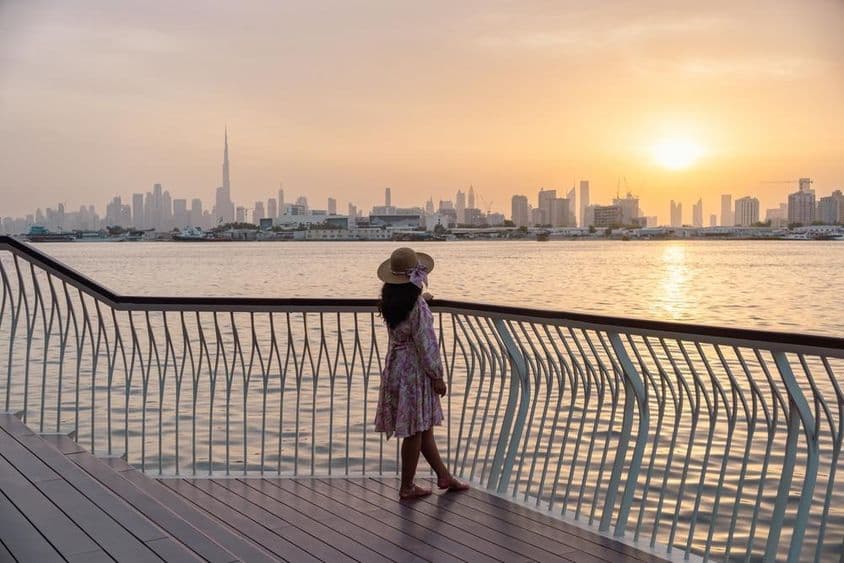Young woman gazing at Dubai skyline under sunset.