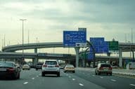 Dubai road with car and overpass advertisement.