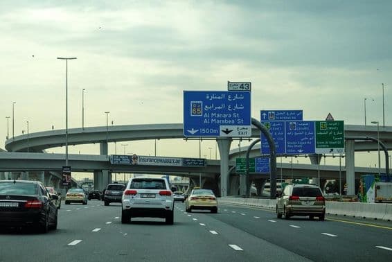 Dubai road with car and overpass advertisement.
