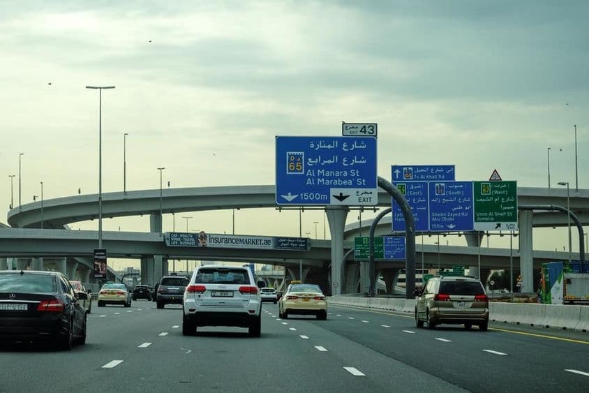 Dubai road with car and overpass advertisement.